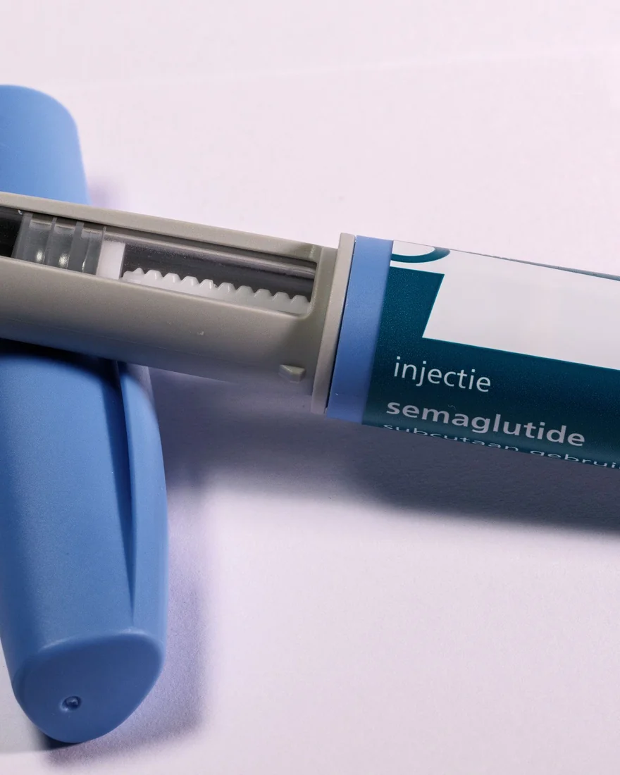 Nahaufnahme eines blauen Fertigpens, beschriftet mit dem Wirkstoff Semaglutid, auf hellem Untergrund. Symbolbild für GLP-1-Abnehmspritzen und die Gewichtsplanung vor einem Brazilian Butt Lift